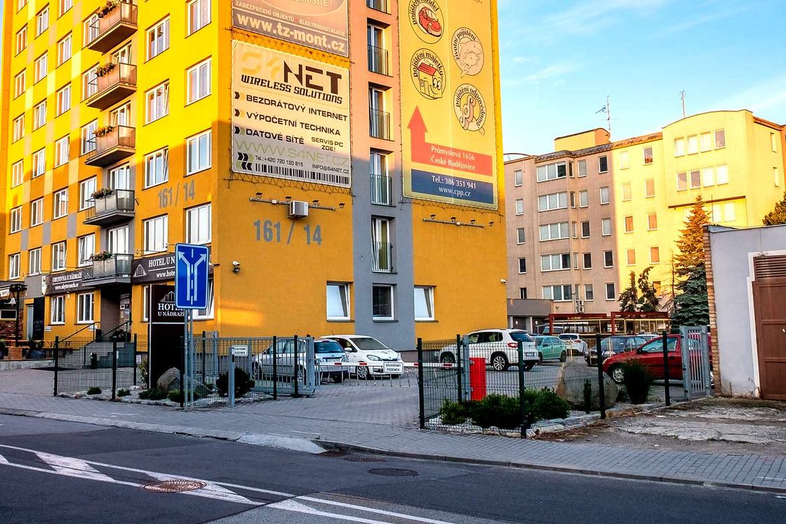 Oplocené parkoviště se zaparkovanými auty přímo u budovy hotelu